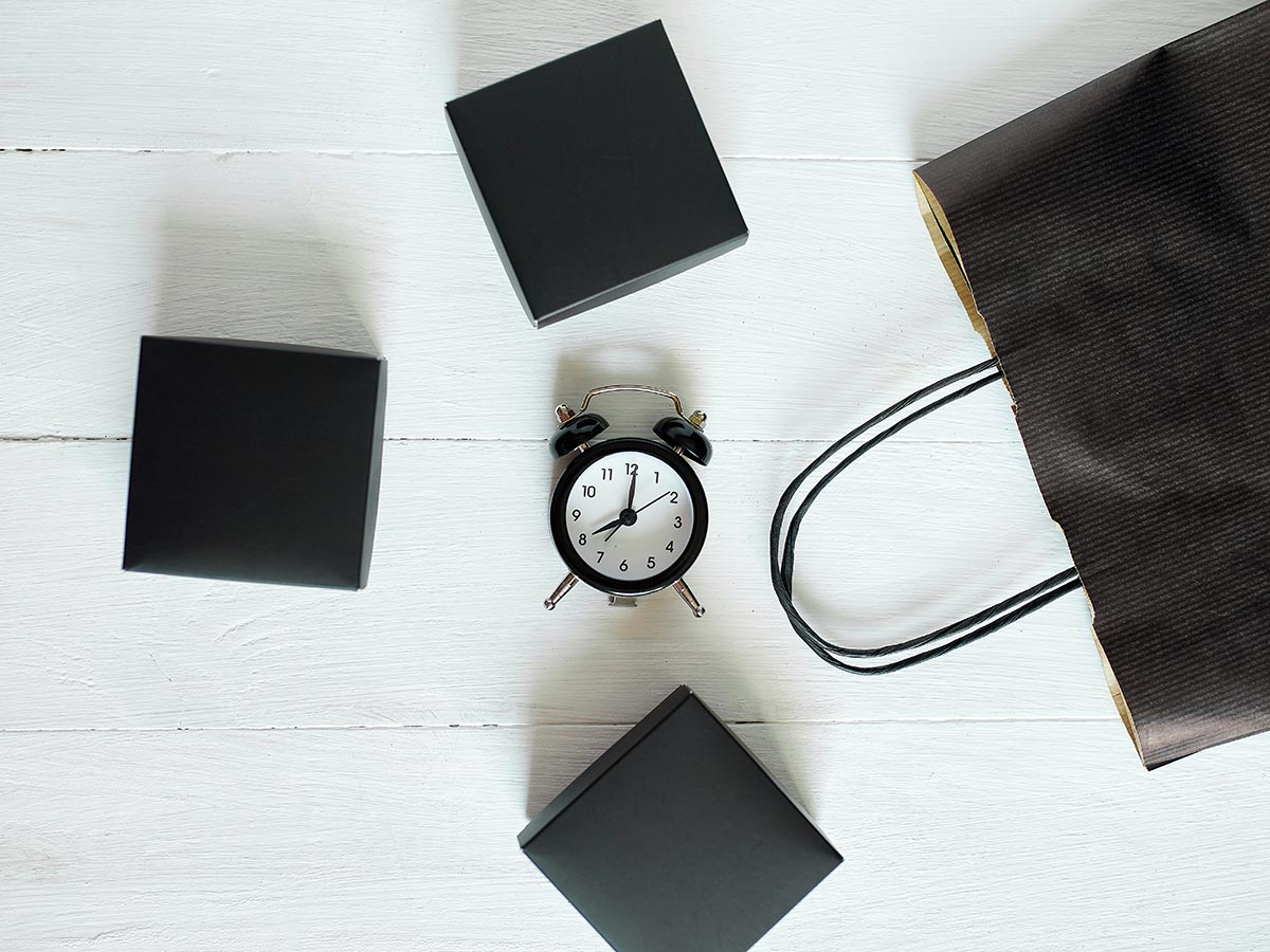 Clock surrounded by shopping bags and boxes.