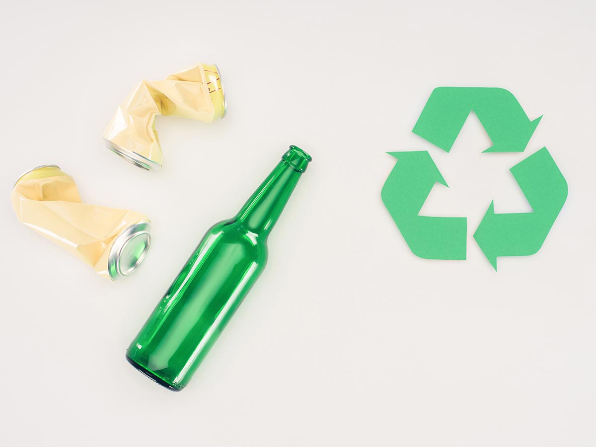 Green glass bottle next to a recycling symbol.