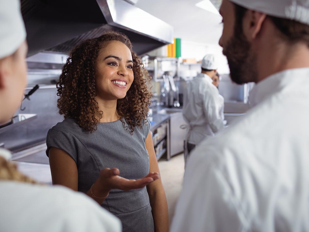 Restaurant manager talking to her cooks in the kitchen.