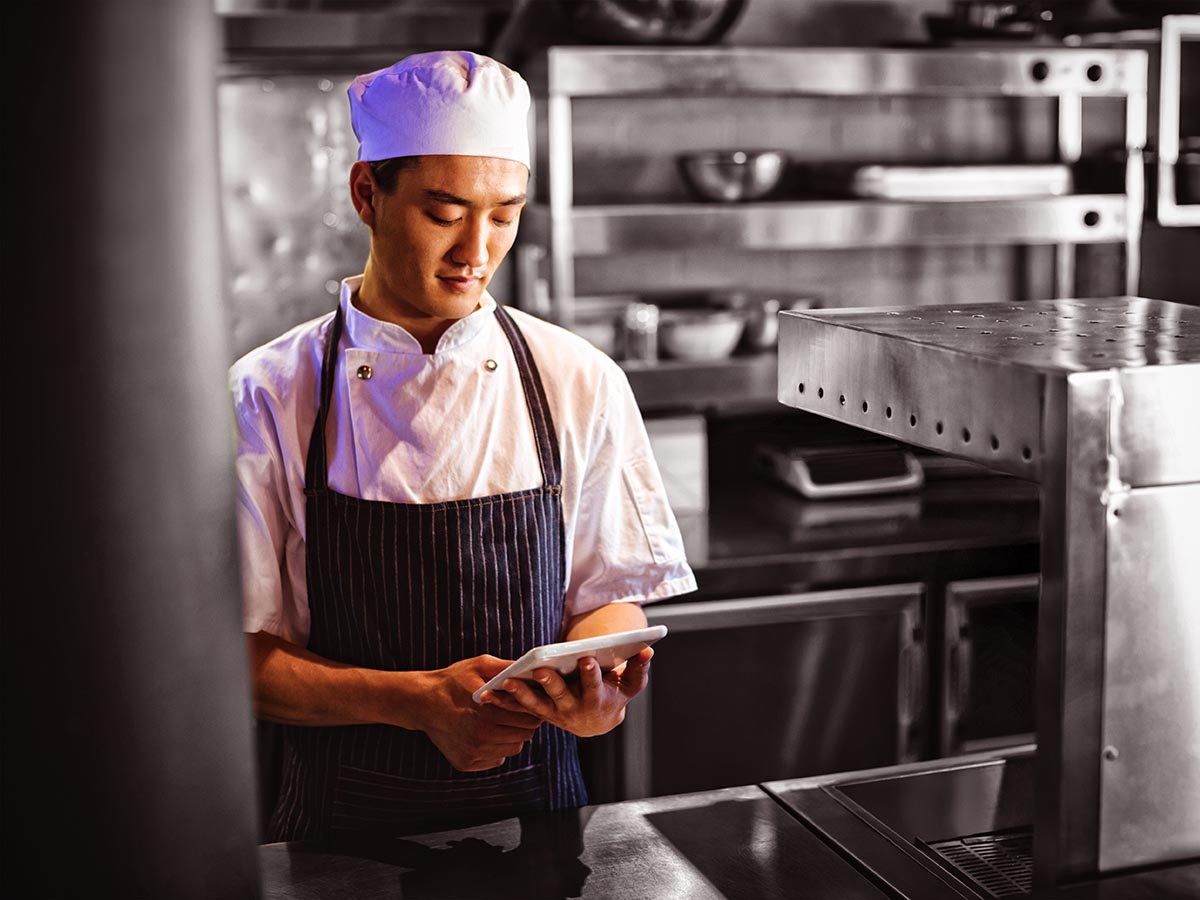 Chef looking at tablet in the kitchen.