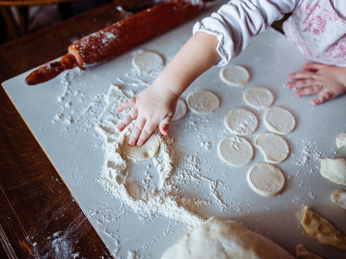 Baker at restaurant rubbing pastry or cookie dough in flour.