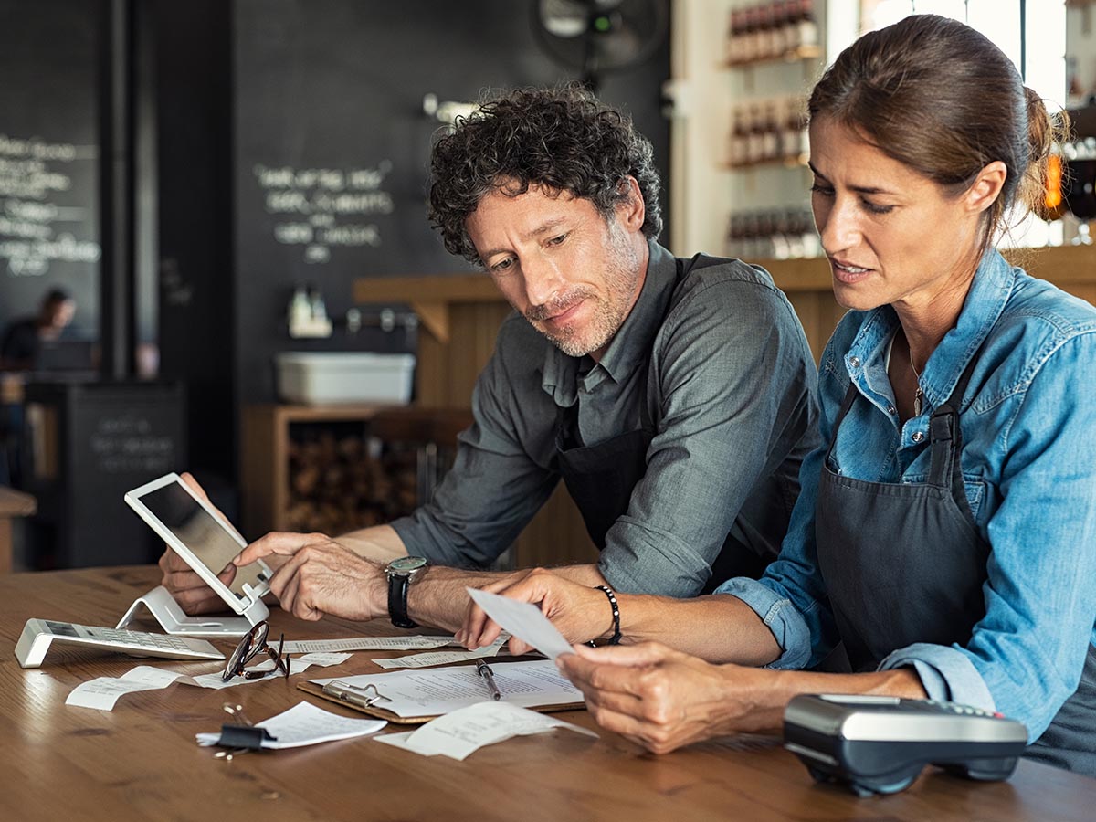 Man and woman restaurant owners closing a day of business with their POS system.