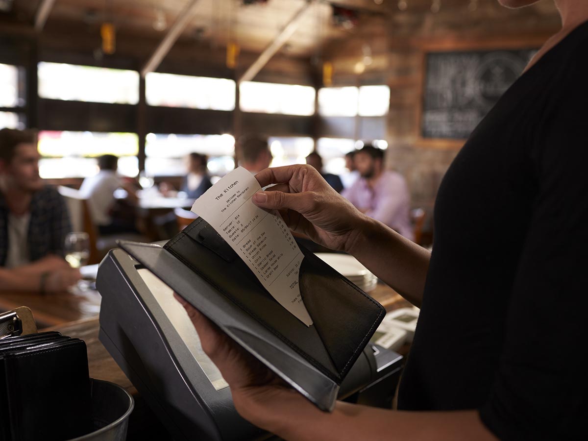 Restaurant bill being put inside black receipt book before going to customer.