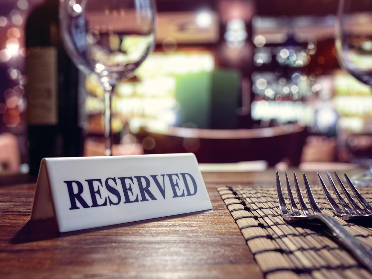 Reserved sign on table next to forks and wine glass.