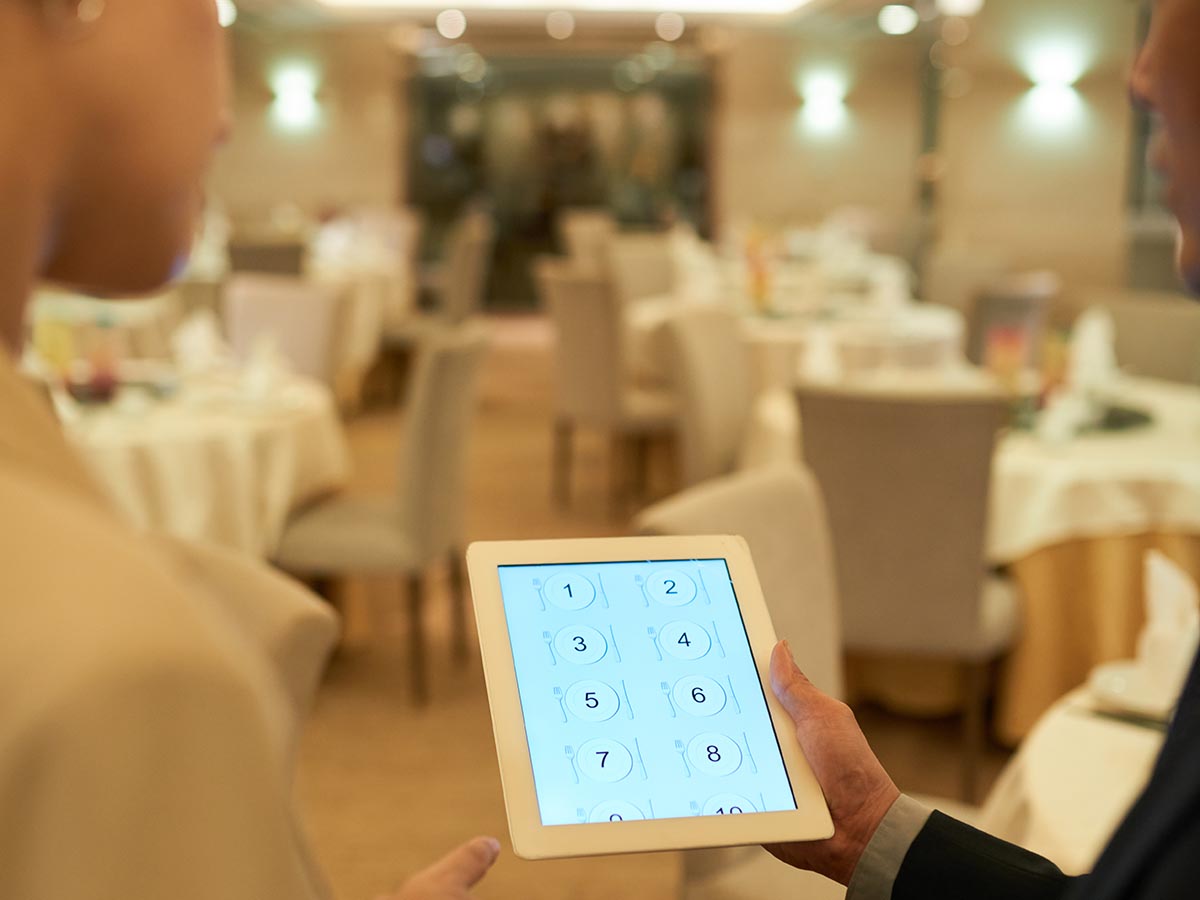 Two people looking at the seating plan for an empty restaurant.