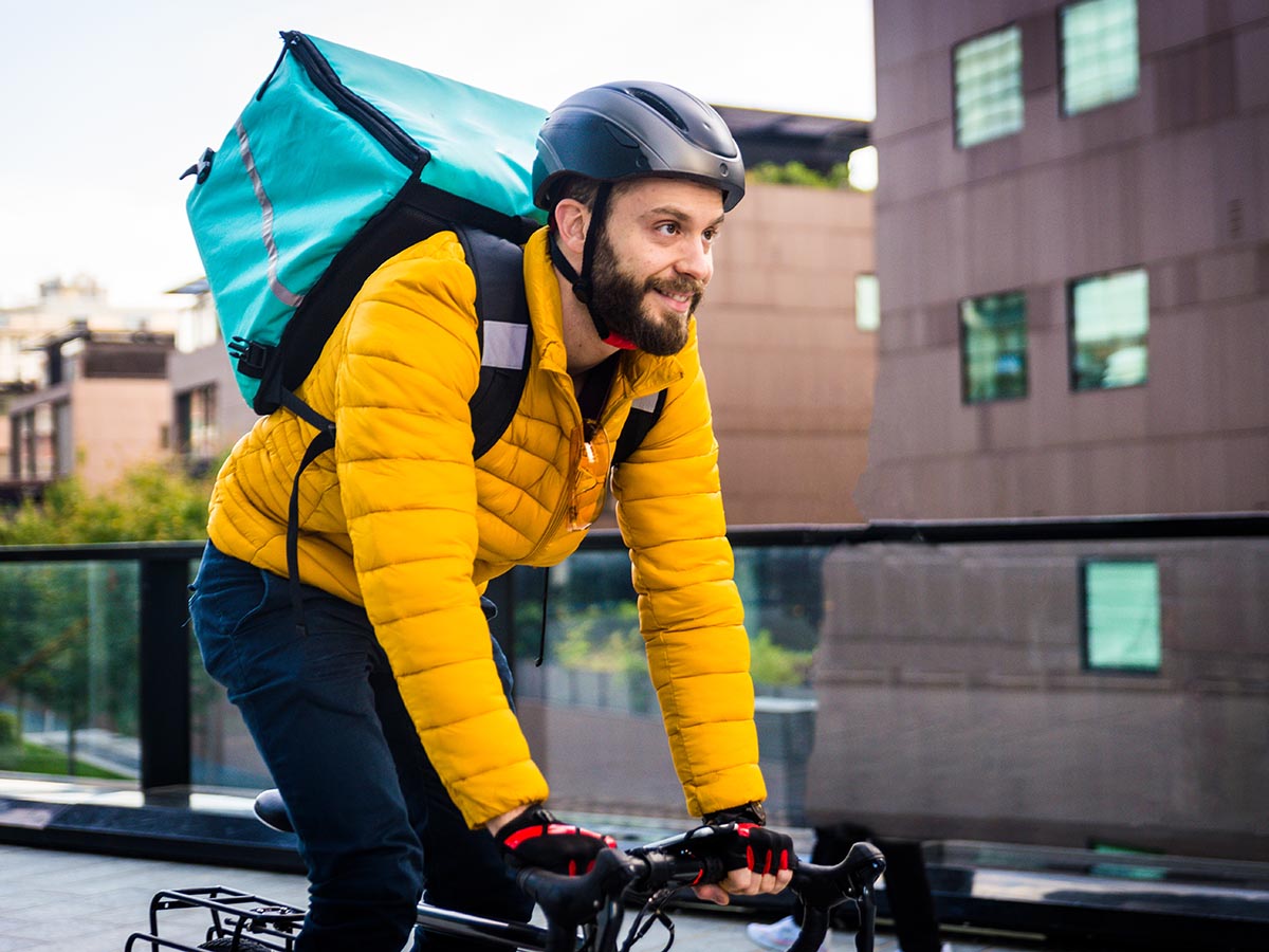 Man on bicycle with food delivery order in his backpack.