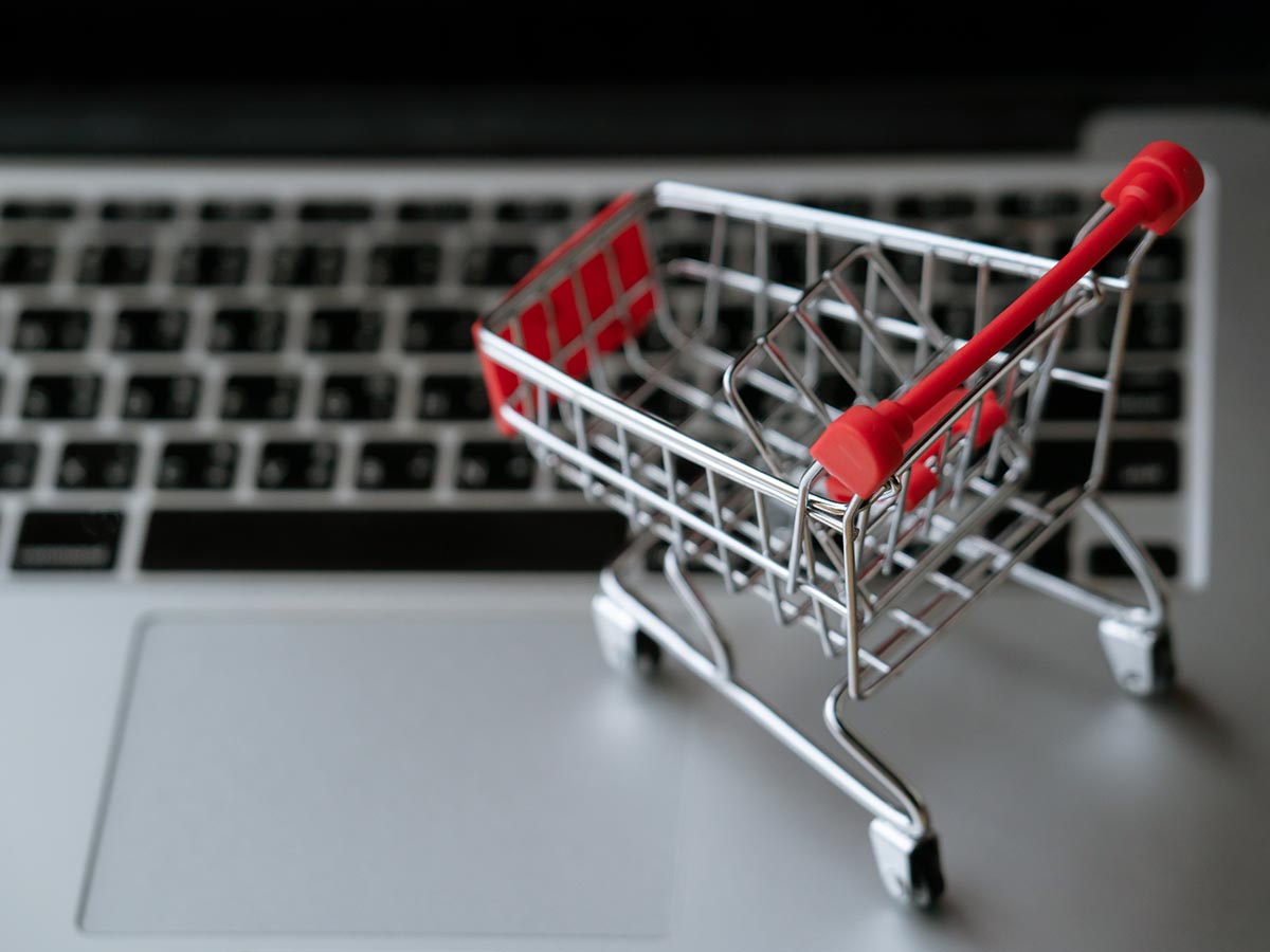 Miniature or toy shopping cart resting on a laptop keyboard.
