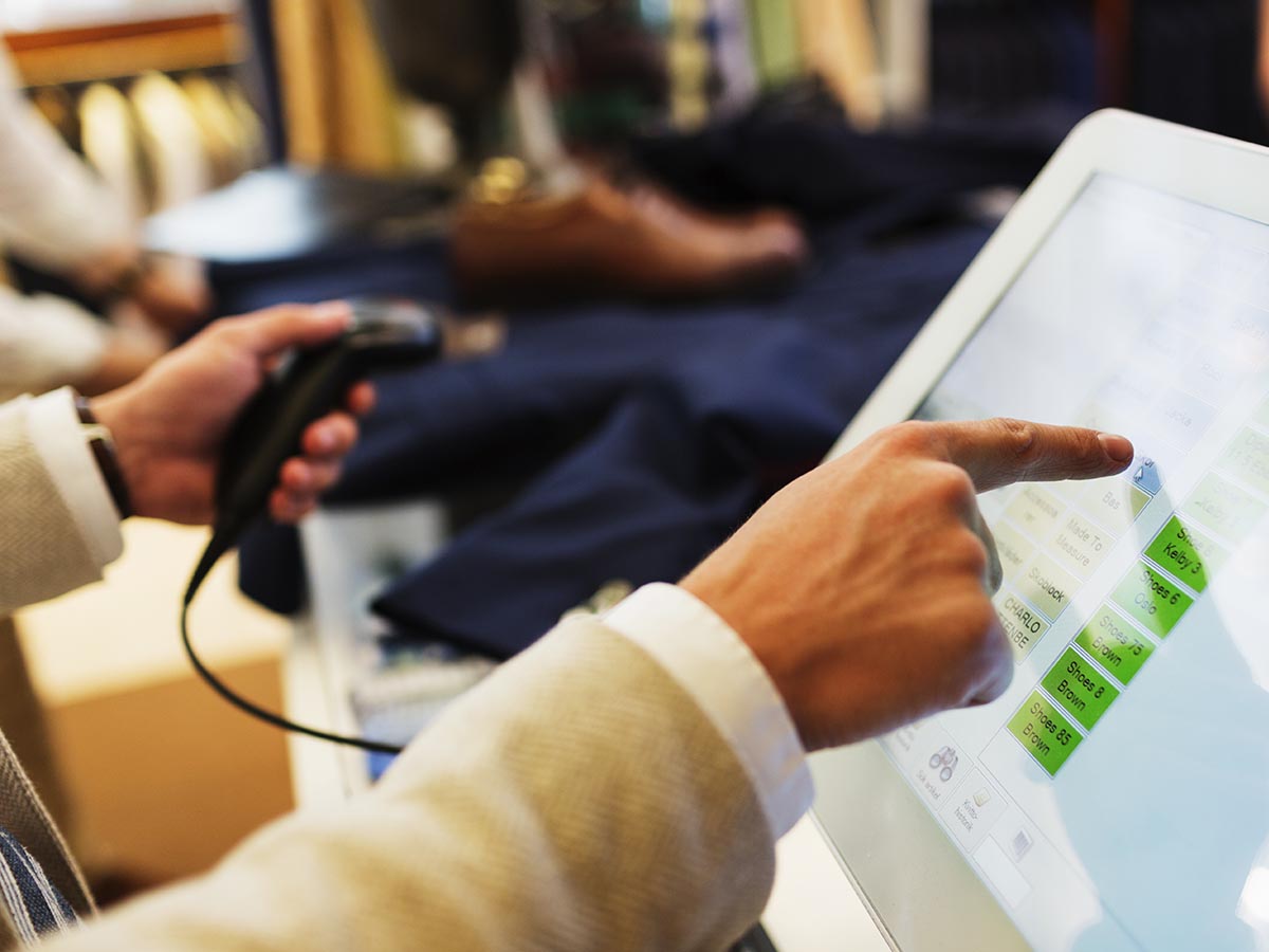 A man scanning a barcode with left hand and pushing button on screen with right hand.