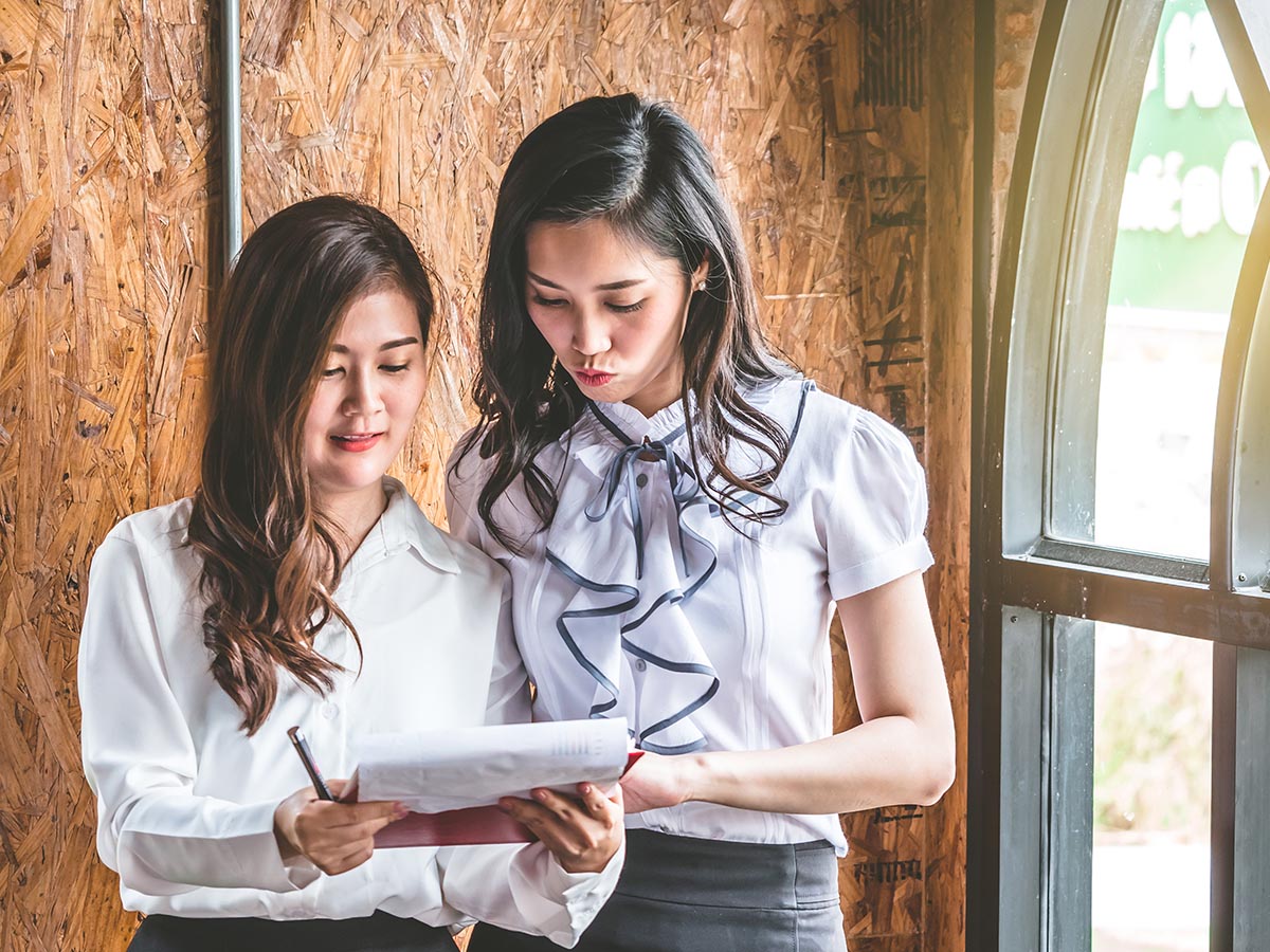 Two women looking at a schedule on a piece of paper.