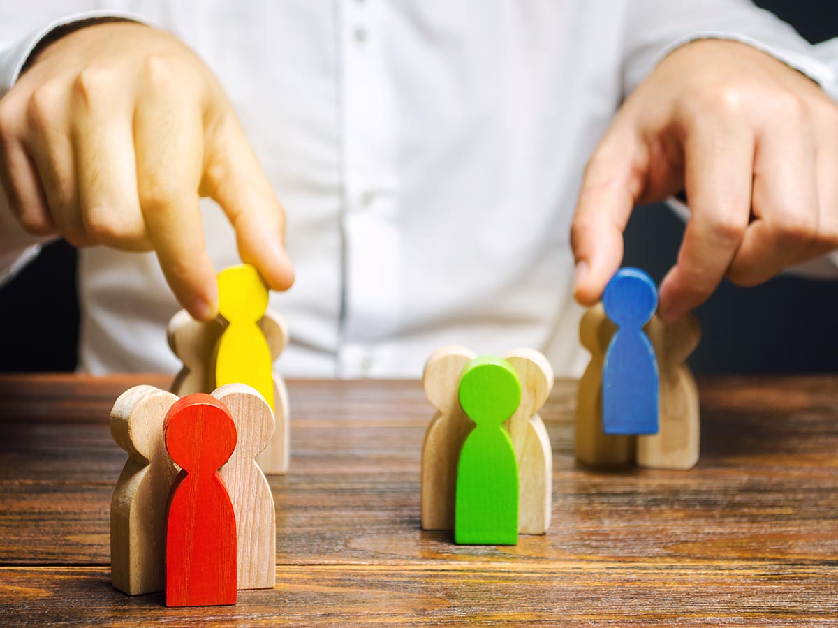 Hands moving wooden figures that represent customer management.